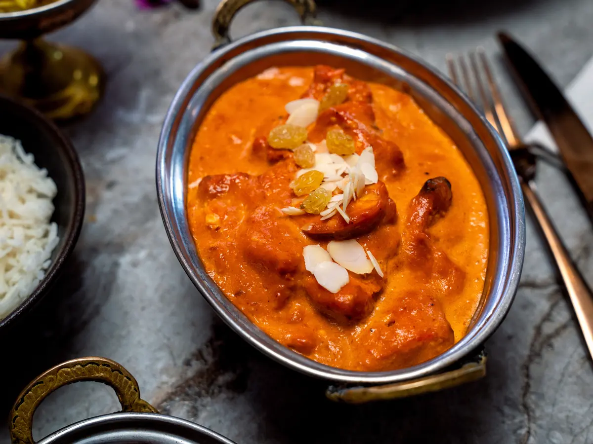 Butter chicken en sauce crémeuse, servi dans un plat de cuivre